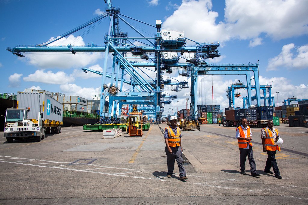 Port workers in hard hats and safety vests at a container terminal