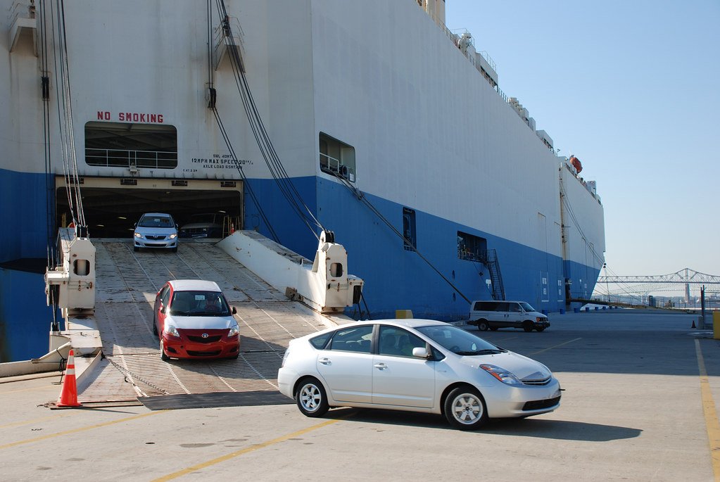Cars driving off the ramp of a roll-on/roll-off vehicle carrier at port