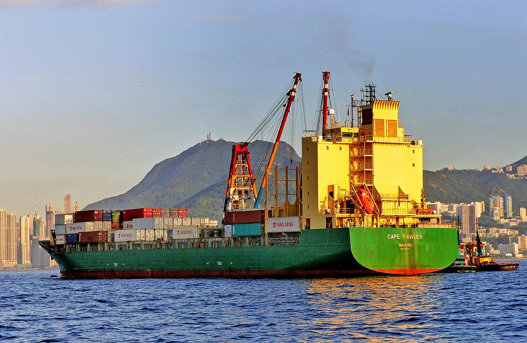 Container ship loaded with cargo sailing through a harbour in evening light